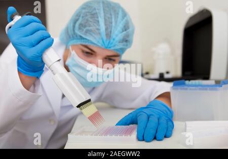 Donna Rosa la preparazione di campioni da una pipetta per analising su attrezzature di alta qualità Foto Stock