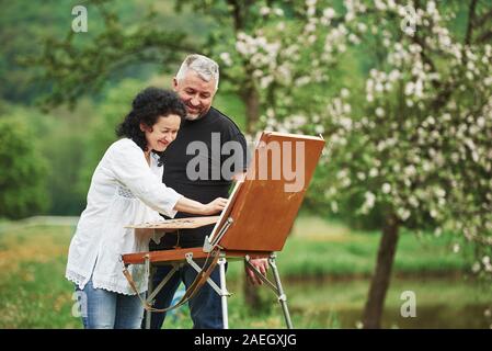 Sorridente e divertirsi. Coppia matura hanno giornate di svago e lavoro su la vernice insieme nel parco Foto Stock