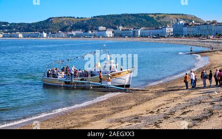 Visitatore scendere Sea-Jay tour in barca, whiile altri attendere a bordo, sulla spiaggia di Llandudno, Wales Harbour Foto Stock