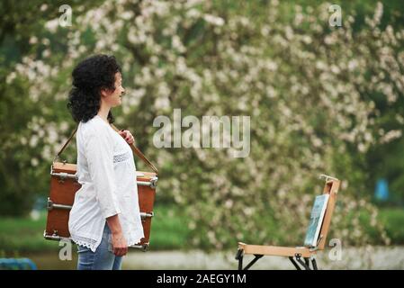 Pittore maturo con il caso di strumenti hanno una passeggiata nel bel Parco di primavera Foto Stock