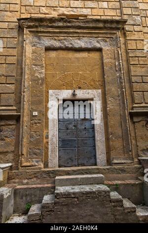 Ingresso di una vecchia chiesa alla piccola piazza di Pienza, in provincia di Siena, Toscana, Italia Foto Stock