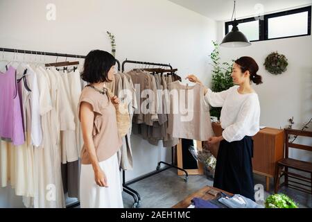 Due donne giapponesi in piedi in una piccola boutique di moda, guardando alla sommità. Foto Stock