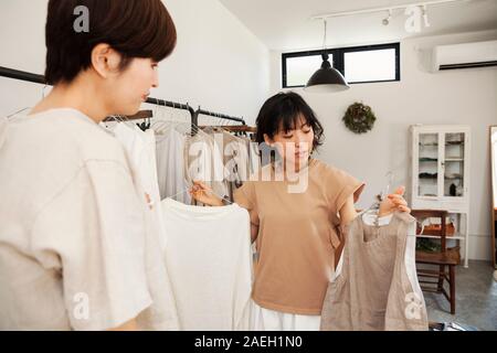 Due donne giapponesi in piedi in una piccola boutique di moda, guardando alla sommità. Foto Stock