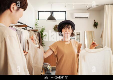 Due donne giapponesi in piedi in una piccola boutique di moda, guardando alla sommità. Foto Stock