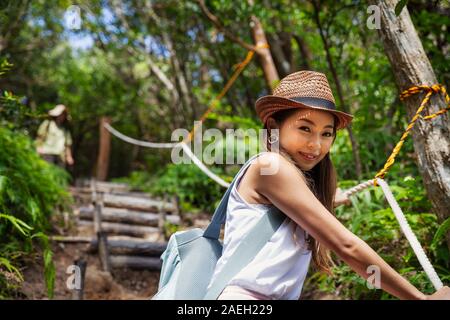 Donna giapponese indossa hat escursionismo in una foresta. Foto Stock