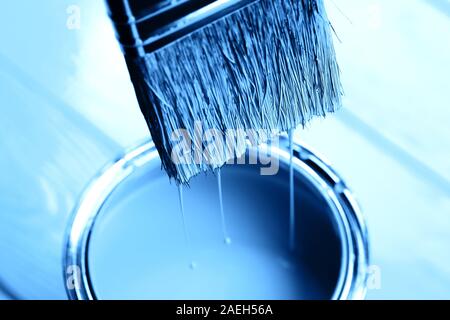 La vernice blu è il gocciolamento da spazzola nella posizione aperta può su dipinta di fresco sfondo di legno. Concetto di restauro. Macro. Foto Stock