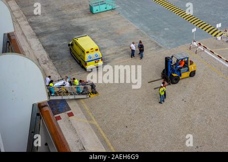 Aruba-11/4/19: il personale di ambulanza e la nave di crociera equipaggio su un dock in Aruba prendendo un passeggero disattivato la nave per il loro trasporto in ospedale per un me Foto Stock
