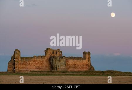 East Lothian, Scozia, Regno Unito, 9 dicembre 2019. Regno Unito Meteo: un cielo chiaro con una quasi completa waxing gibbous moon rising sopra le rovine di una parete di tamponamento del XIV secolo il castello di Tantallon affacciato sul Firth of Forth Foto Stock