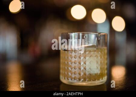 Un vetro highball rimed con condensazione si siede su un tavolo in oro light Foto Stock