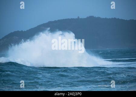 Close-up di una grande onda rottura nell'oceano contro una roccia Foto Stock