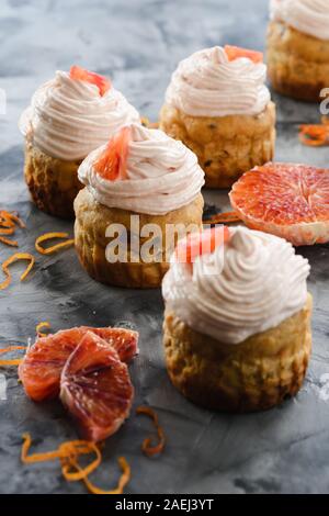 Le sane prive di zucchero dolci. Muffin con crema di formaggio e sangue glassa arancione su sfondo scuro closeup Foto Stock
