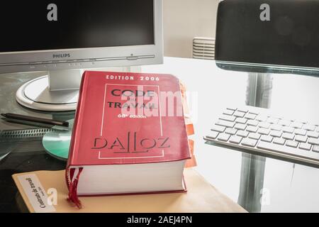 Parigi, Francia - 13 Marzo 2016: codice francese del lavoro libro è raffigurato con computer su una scrivania in studio su una giornata invernale Foto Stock