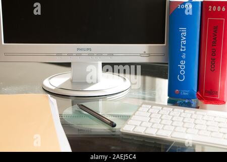 Parigi, Francia - 13 Marzo 2016: codice francese del lavoro libro è raffigurato con computer su una scrivania in studio su una giornata invernale Foto Stock