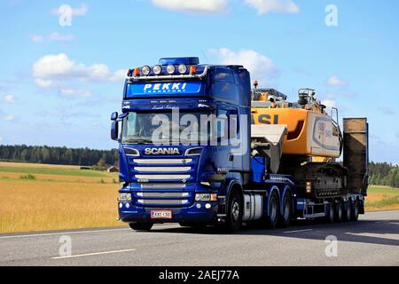 Blue Scania R620 carrello di trasporto Pekki Oy trasporta RASI 946 Escavatore cingolato sul rimorchio lungo l'autostrada 10 in Koski TL, Finlandia. Luglio 29, 2019. Foto Stock