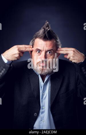 Un ritratto di divertenti uomo barbuto con iroquois indossare tuta che mostra il gesto della pistola. Le persone e le emozioni concetto Foto Stock