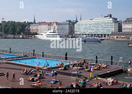 La gente a prendere il sole a Allas mare Piscina con grande yacht e Hotel Palace in background, Helsinki, Scandinavia, Finlandia, Europa Foto Stock