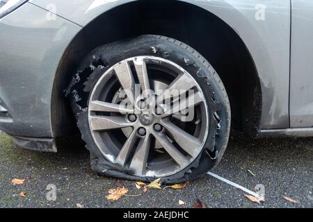 Un vicino di una vettura a ruote con un pneumatico che è esplosa e necessita di sostituzione, Foto Stock