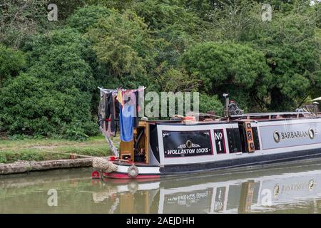 Narrowboat ormeggiato sul Grand Union Canal, Cosgrove, Northamptonshire, Regno Unito; con lavaggio asciugatura su una linea rotante sul retro. Foto Stock