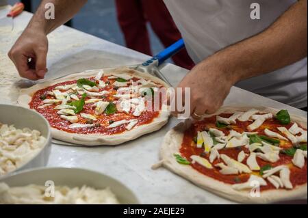 Preparare la Pizza Margherita su un piano di marmo. Pizzaiolo mette impasto per pizza sulla buccia. Messa a fuoco selettiva Foto Stock