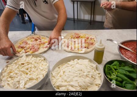 Preparare la pizza su un piano di marmo. Pizzaiolo mette impasto per pizza sulla buccia. Foto Stock