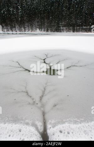 Un parzialmente congelati Lago Planšar (Planšarsko jezero) in Zgornje Jezersko, Slovenia, con un foro di ramificati nel ghiaccio. Foto Stock