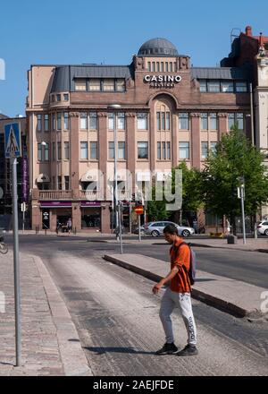Vista laterale del giovane uomo attraversando via nella parte anteriore del Casino Helsinki, Rautatientori Square, Helsinki, Finlandia,Scandinavia, Europa Foto Stock