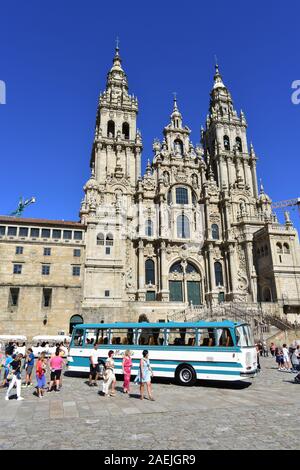 Cattedrale con i pellegrini e vecchio bus. Vista da Praza do Obradoiro con il blu del cielo. Santiago de Compostela, Spagna. Jul 28, 2019. Foto Stock