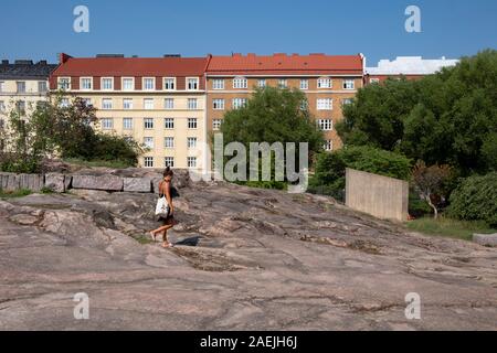 Vista laterale della donna che cammina sulla roccia con edifici di sfondo attorno alla chiesa di Temppeliaukio ad Helsinki in Finlandia e Scandinavia, Europa Foto Stock