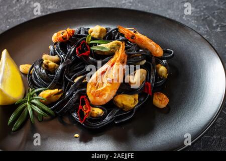 Spaghetti al nero. Piatti di pasta con le cozze e gamberi su sfondo di pietra. Mediterraneo la delicatezza del cibo. Foto Stock