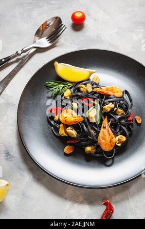 Spaghetti al nero. Piatti di pasta con le cozze e gamberi su sfondo di calcestruzzo. Mediterraneo la delicatezza del cibo. Foto Stock