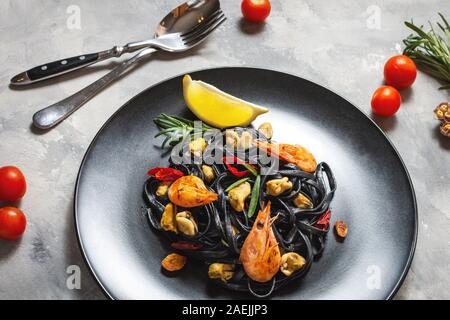 Spaghetti al nero. Piatti di pasta con le cozze e gamberi su sfondo di calcestruzzo. Mediterraneo la delicatezza del cibo. Foto Stock