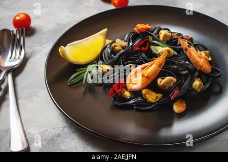Spaghetti al nero. Piatti di pasta con le cozze e gamberi su sfondo di calcestruzzo. Mediterraneo la delicatezza del cibo. Foto Stock