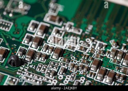 Vista dettagliata dei componenti elettronici su una scheda a circuito stampato verde utilizzata nei moderni dispositivi elettronici Foto Stock