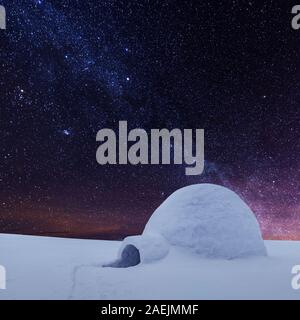 Scena invernale con snowy igloo e la via lattea nel cielo notturno. Fantastico paesaggio invernale incandescente da star light. Santa Casa da neve, ideale Anno nuovo e lo sfondo di Natale Foto Stock