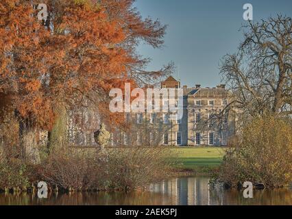 Petworth House e il lago con golden autumn alberi Foto Stock