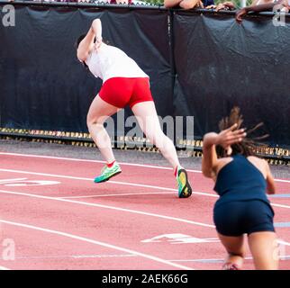 Due high school di velocisti femminile stanno iniziando una gara nelle corsie 4 e 5 su una pista rossa durante una pista e campo gara sprint. Foto Stock