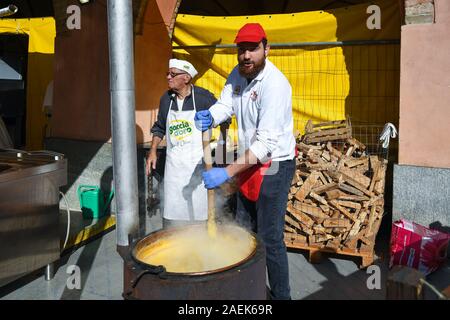 Giovane uomo barbuto la cucina tipica polenta di mais nel centro storico di Alba durante il famoso tartufo bianco Fiera, Cuneo, Piemonte, Italia Foto Stock