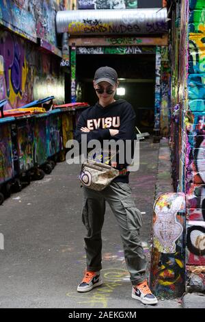 Giovane uomo colpisce un pongono di fronte strada e sono graffiti in Melbourne, vicolo. Foto Stock