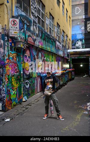 Adolescente colpisce una posa surrouned by street graffiti in Melbourne vicolo. Foto Stock