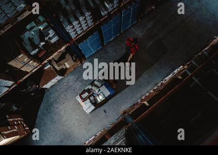 Lavoratore forte sulla grande magazzino. Sacco di scatole al buio interiore e top vista aerea Foto Stock