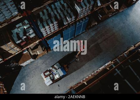 Lavoratore forte sulla grande magazzino. Sacco di scatole al buio interiore e top vista aerea Foto Stock