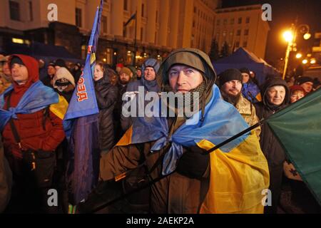 Kiev, Ucraina. Decimo Dec, 2019. La gente guarda una schermata visualizzata da una conferenza stampa del leader della Normandia quattro, durante una manifestazione davanti il presidente ucraino ufficio a Kiev, Ucraina, il 10 dicembre 2019. Gli ucraini riuniti presso il presidente ucraino ufficio da notte Dicembre 08, per ottenere la Normandia formato risultati della riunione che si è tenuta a Parigi il 09 dicembre, 2019. Credito: Serg Glovny/ZUMA filo/Alamy Live News Foto Stock