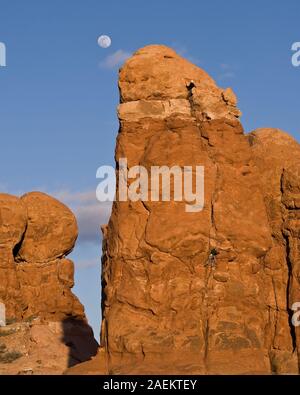 Uno sport rocciatore si arrampica Owl Rock nel Parco Nazionale di Arches nei pressi di Moab, Utah. Un altro scalatore ha asceso con successo ed è belaying lui dal Foto Stock