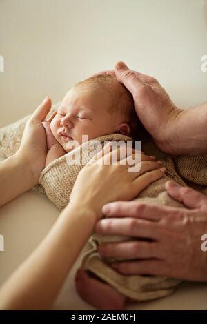Carino neonato ragazza distesa sul suo padre e madre le mani, a casa Foto Stock
