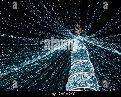 Moderna struttura ad albero di Natale con le luci a led che scendono dalla parte superiore dell'albero. vista dal basso Foto Stock