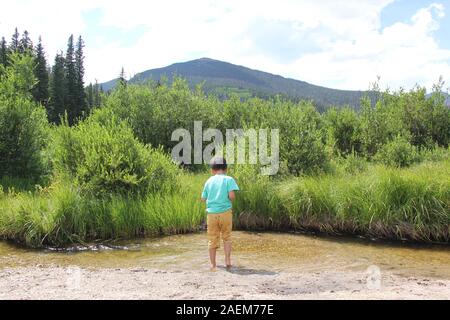 Parco Nazionale di Yellowstone, ragazzo in piedi dal piccolo ruscello Foto Stock