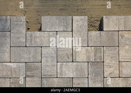 Regolare i blocchi di forma, consistenza, sfondo. Pavimentazione in lastre di blocchi di colore grigio di forma piatta, close-up. Frammento di La posa in opera di nuova pavimentazione in lastre Foto Stock