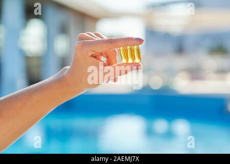 Sunny golden vitamina D olio in capsule di Omega-3 nella donna la mano Foto Stock