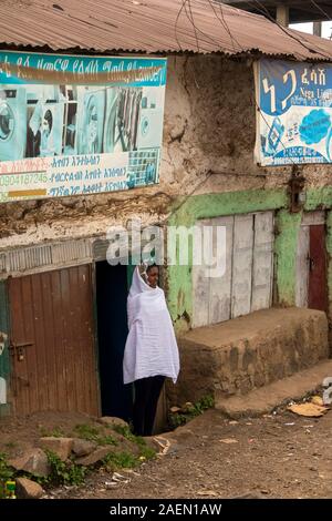 Etiopia, Amhara Region, sbarcare, centro città, donna che indossa Netel panno bianco scialle in corrispondenza della porta a guardare passare funebri Foto Stock