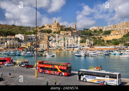 Mgarr, Gozo, Malta - 15 Ottobre 2019: città portuale con gli autobus turistici in attesa per i turisti al Porto in Isola di Gozo, regione settentrionale di Ma Foto Stock